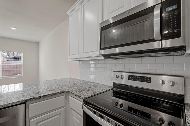 kitchen featuring decorative backsplash, stainless steel appliances, white cabinetry, and dark wood-type flooring