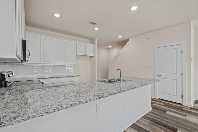 kitchen featuring decorative backsplash, light stone countertops, sink, and white cabinets