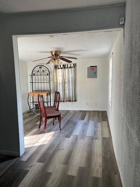 interior space with electric panel, ceiling fan, dark wood-type flooring, and a textured ceiling