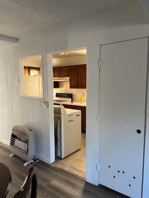 kitchen featuring stove, backsplash, light wood-type flooring, washer / clothes dryer, and heating unit