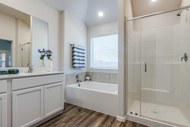 bathroom with vanity, hardwood / wood-style flooring, vaulted ceiling, and independent shower and bath