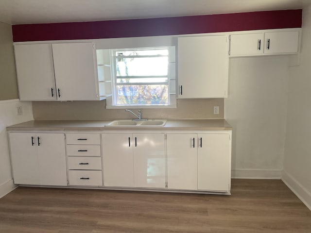 kitchen featuring decorative backsplash, light wood-type flooring, white cabinetry, and sink