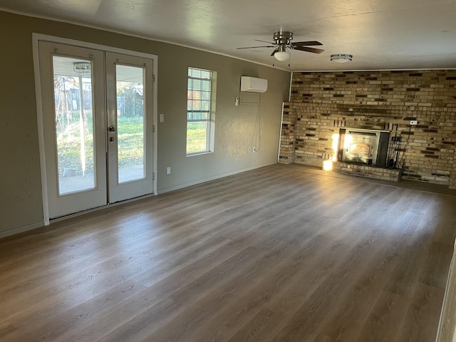 unfurnished living room featuring french doors, a brick fireplace, hardwood / wood-style flooring, ceiling fan, and a wall mounted AC