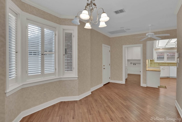 unfurnished dining area featuring ceiling fan with notable chandelier, light wood-type flooring, and crown molding