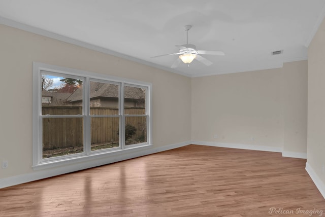 empty room with baseboards, light wood-style flooring, visible vents, and crown molding