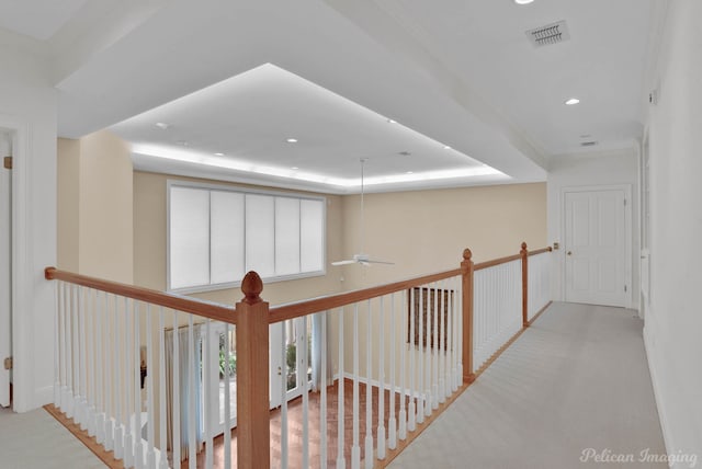 corridor featuring light carpet and a raised ceiling