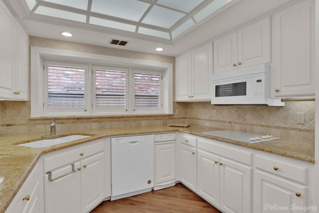 kitchen featuring white appliances, white cabinets, sink, light hardwood / wood-style flooring, and tasteful backsplash