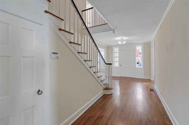 foyer entrance featuring crown molding, visible vents, stairway, wood finished floors, and baseboards