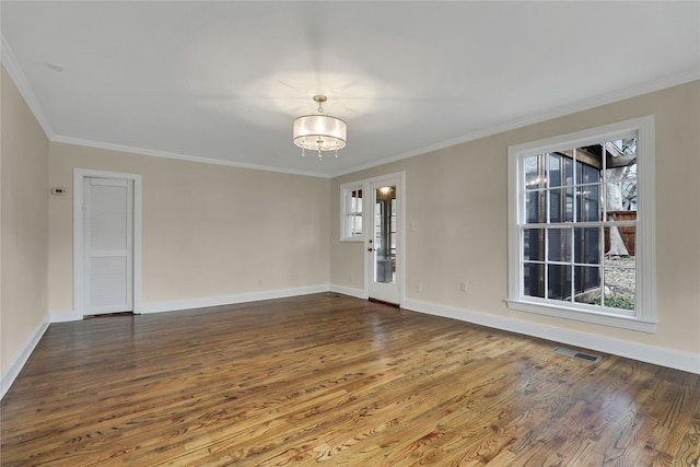 unfurnished room with ornamental molding, wood finished floors, visible vents, and baseboards