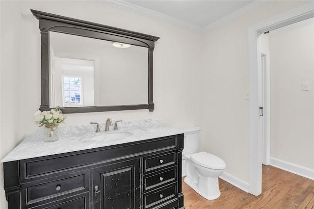 half bath featuring baseboards, toilet, ornamental molding, wood finished floors, and vanity