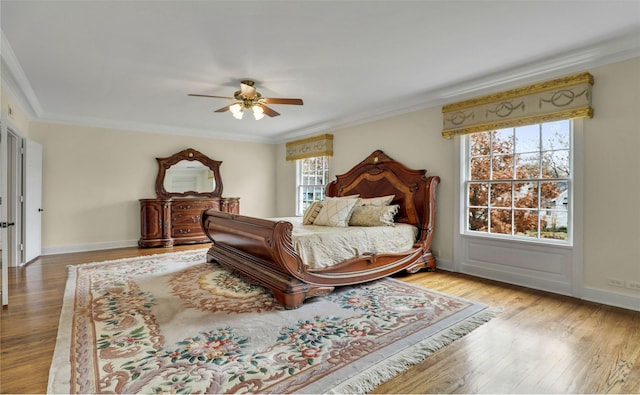 bedroom featuring ornamental molding, wood finished floors, a ceiling fan, and baseboards