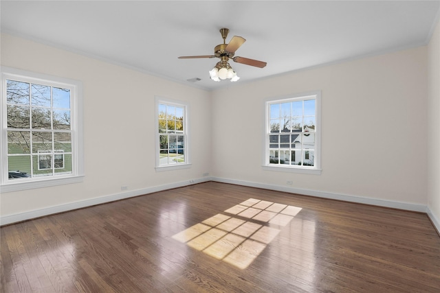 empty room featuring visible vents, crown molding, baseboards, and wood finished floors