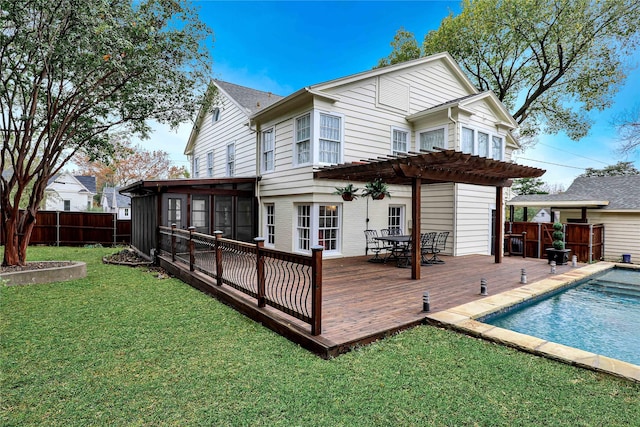 rear view of property featuring fence, a sunroom, a lawn, a wooden deck, and a pergola