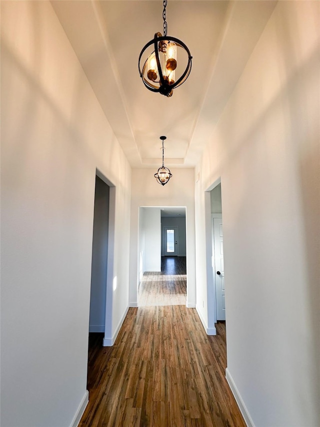 hallway with a chandelier and dark wood-type flooring