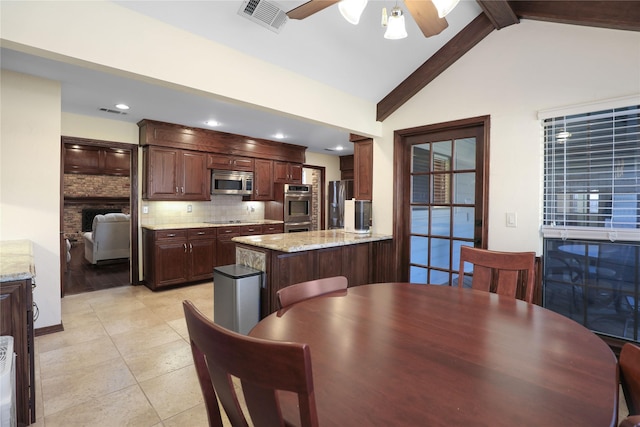 tiled dining room featuring a fireplace, vaulted ceiling with beams, and ceiling fan