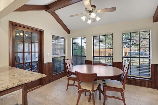 tiled dining space with ceiling fan, wooden walls, and lofted ceiling with beams