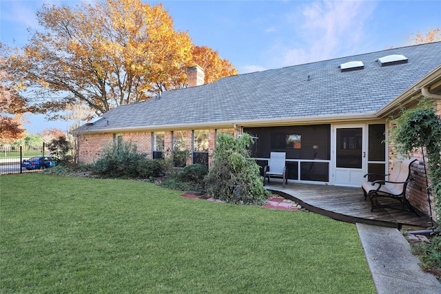 rear view of house featuring a lawn and a sunroom