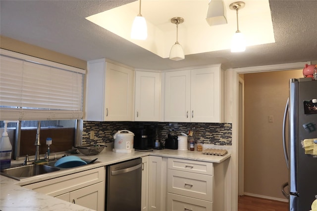 kitchen with pendant lighting, sink, decorative backsplash, appliances with stainless steel finishes, and white cabinetry