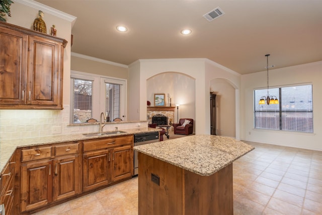 kitchen with dishwashing machine, a sink, brown cabinets, light stone counters, and arched walkways