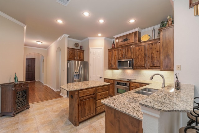 kitchen with kitchen peninsula, light stone counters, a breakfast bar, stainless steel appliances, and sink