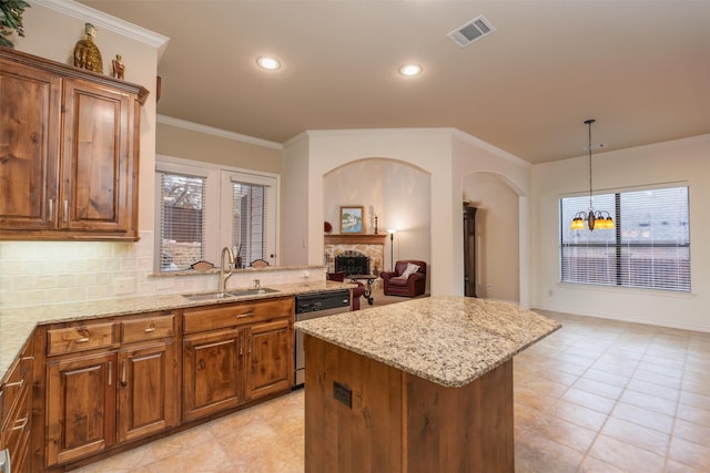 kitchen with backsplash, stainless steel dishwasher, sink, a chandelier, and a kitchen island