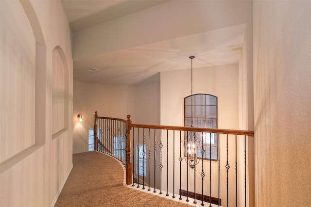 hall with carpet and a chandelier