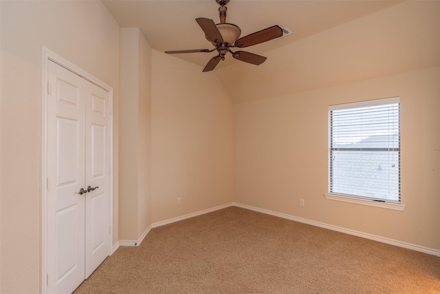 empty room with light carpet, lofted ceiling, ceiling fan, and baseboards