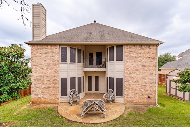 back of house featuring a lawn, a patio area, a balcony, and a storage shed