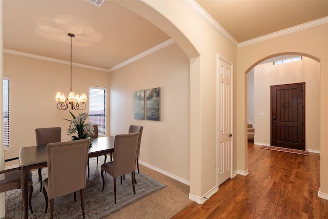 dining room with arched walkways, crown molding, wood finished floors, baseboards, and stairway