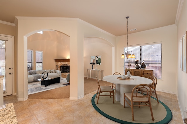 dining area featuring crown molding, arched walkways, a fireplace, baseboards, and a chandelier