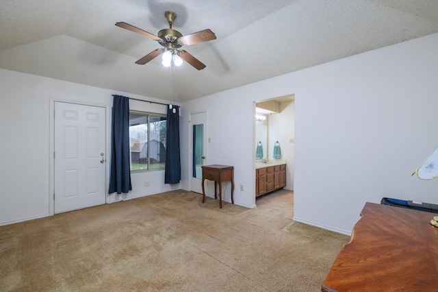 bedroom featuring light carpet, ensuite bath, a textured ceiling, vaulted ceiling, and ceiling fan