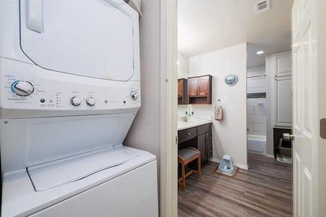 washroom featuring dark wood-type flooring and stacked washer and clothes dryer