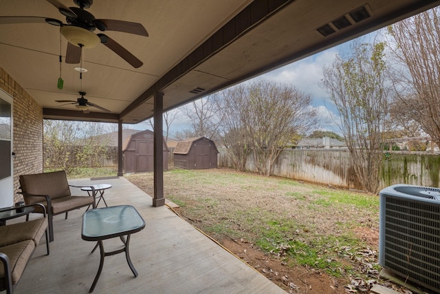 view of patio with central AC unit, ceiling fan, and a shed