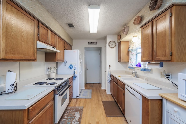 kitchen with a textured ceiling, sink, light hardwood / wood-style floors, and white appliances