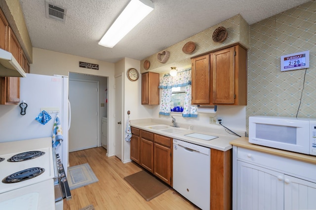 kitchen featuring a textured ceiling, light hardwood / wood-style floors, white appliances, and sink