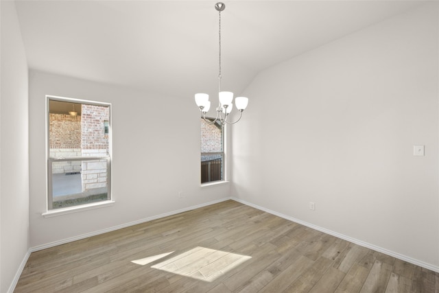 spare room with light hardwood / wood-style flooring, vaulted ceiling, and an inviting chandelier