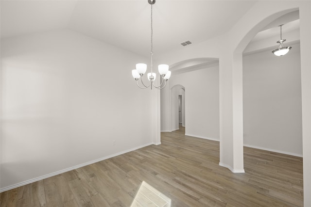 unfurnished dining area featuring an inviting chandelier, hardwood / wood-style floors, and vaulted ceiling