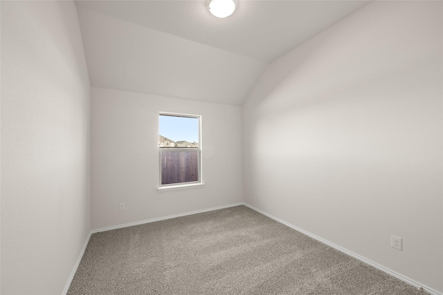 carpeted spare room featuring lofted ceiling