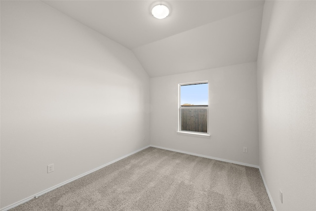 carpeted spare room featuring lofted ceiling