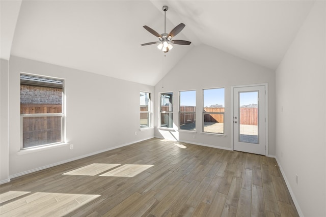 unfurnished room with lofted ceiling, a wealth of natural light, light hardwood / wood-style floors, and ceiling fan