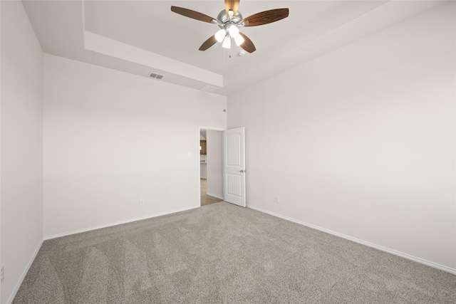 unfurnished room with light carpet, ceiling fan, and a tray ceiling