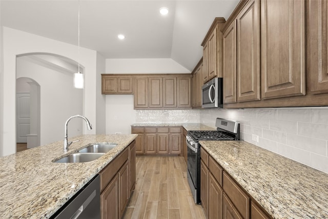 kitchen with sink, hanging light fixtures, stainless steel appliances, light stone counters, and tasteful backsplash