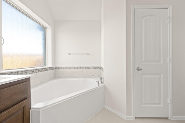 bathroom featuring lofted ceiling, vanity, and a bathtub