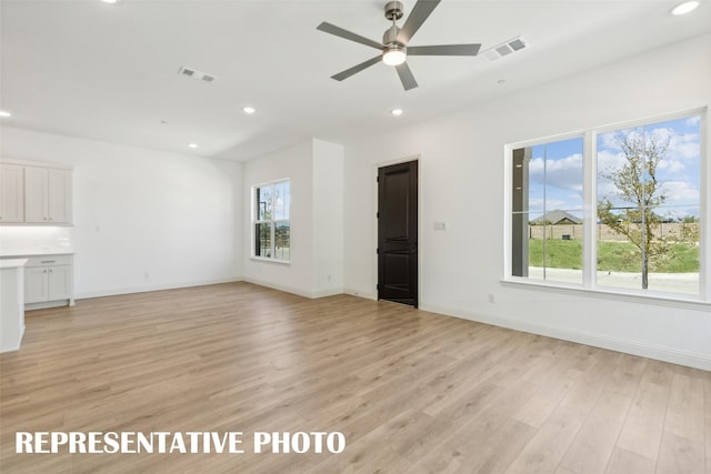 unfurnished living room with a wealth of natural light, ceiling fan, and light wood-type flooring