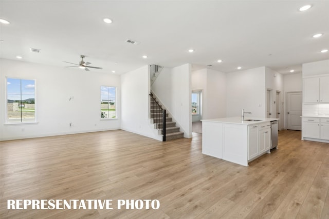 kitchen with white cabinets, light wood-type flooring, a wealth of natural light, and dishwasher