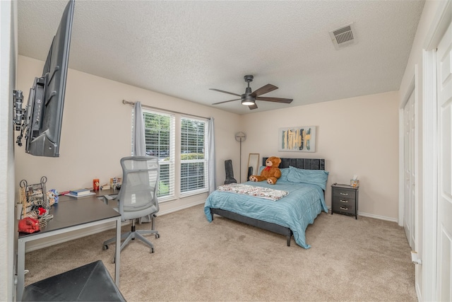 carpeted bedroom featuring ceiling fan and a textured ceiling