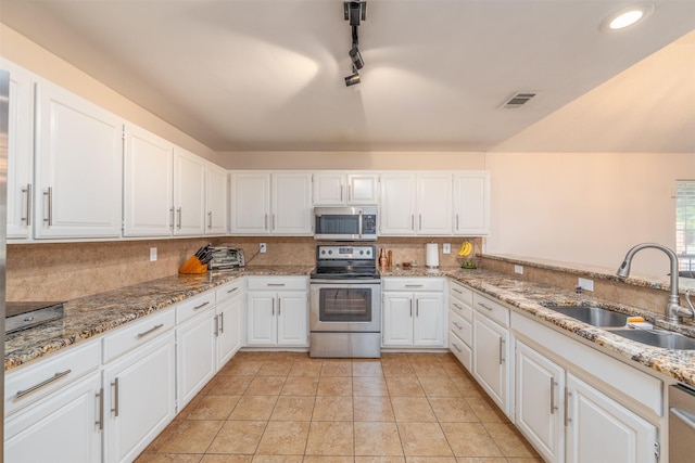 kitchen featuring appliances with stainless steel finishes, rail lighting, light stone counters, sink, and white cabinets