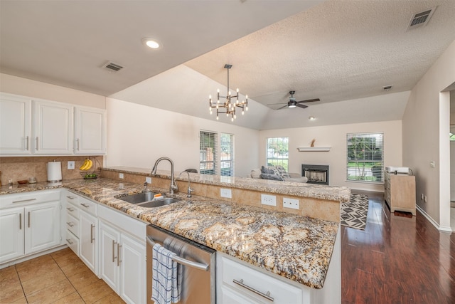 kitchen with dishwasher, kitchen peninsula, lofted ceiling, and sink