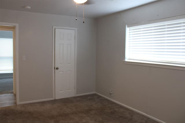 empty room with dark carpet and ceiling fan