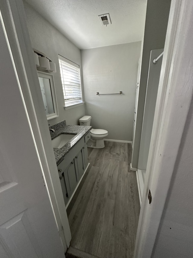 bathroom featuring vanity, toilet, hardwood / wood-style floors, and a textured ceiling